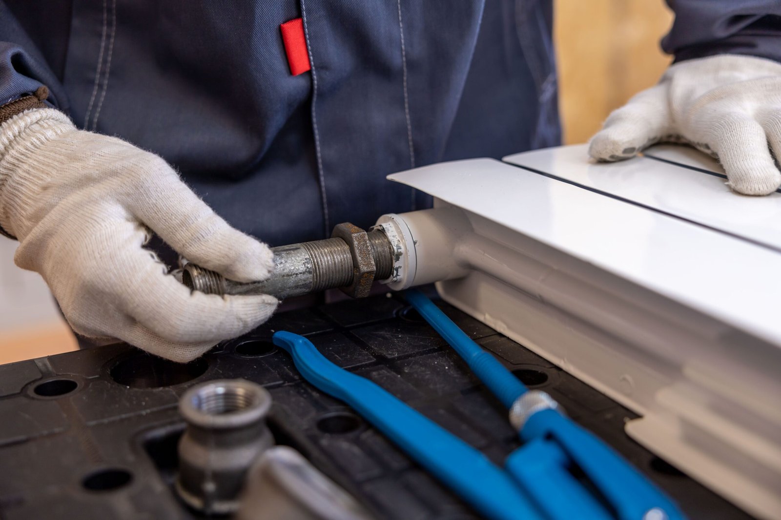 Plumber installing a radiator pipe with hand tools, Aurora, CO