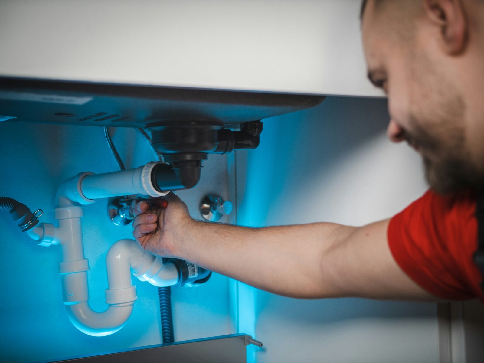 Plumber repairing a pipe inside a wall cavity during an emergency call, Aurora, CO